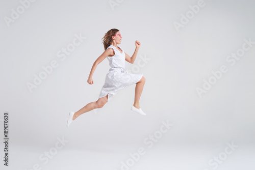 Crazy joyful girl in summer dress jumping isolated over background