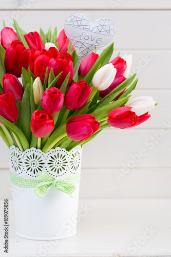 Fototapeta Naklejka Na Ścianę i Meble -  Fresh red tulip flowers bouquet on shelf in front of wooden wall.