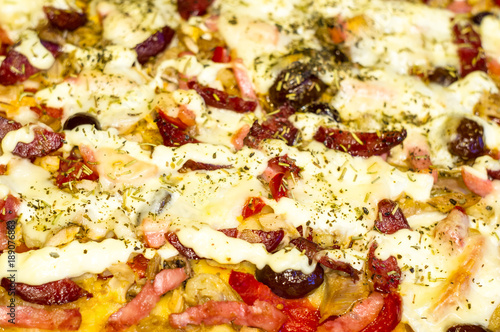 homemade pizza with peppers, plums, ham, sausage, cheese and spices, closeup