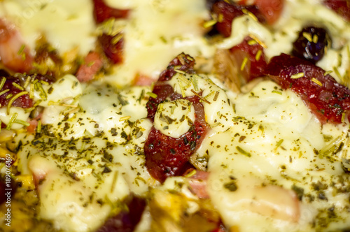homemade pizza with peppers, plums, ham, sausage, cheese and spices, closeup