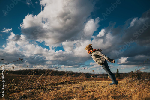 Boy standing in rural landscape with his arms outstretched photo