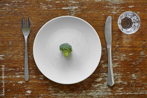 Billede på lærred single broccoli on plate with knife and fork metaphor for dieting