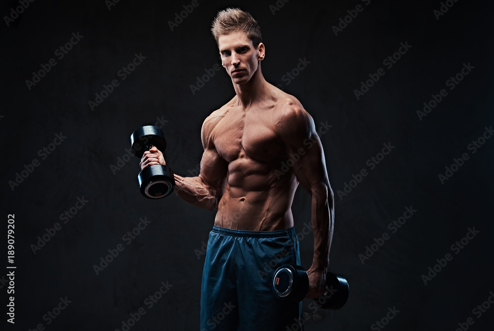 Athletic shirtless male biceps dumbbell workout.