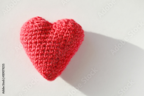 Red knitted heart lies on white paper. Template for a postcard on Valentine s Day.