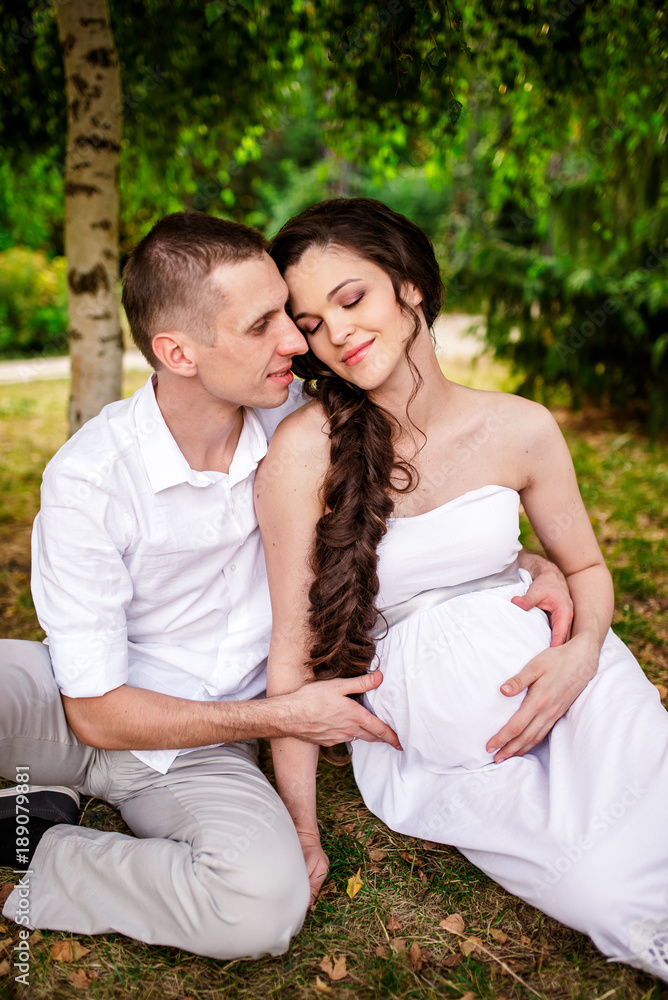 A happy pregnant couple is walking in nature. A happy pregnant couple is walking in nature.