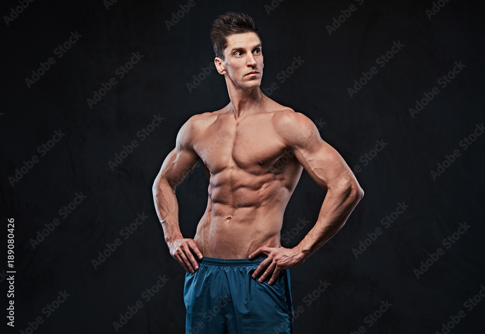 Shirtless muscular male over dark background. Shirtless muscular male over dark background.