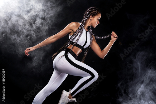 A strong athletic, woman sprinter, running on black background wearing in the sportswear, fitness and sport motivation. Runner concept with copy space.