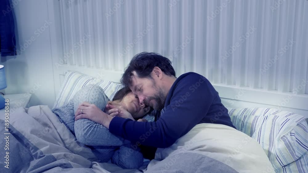 Husband and wife cuddling in bed at night Husband and wife cuddling in bed at night