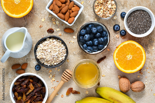 Food background. Ingredients for breakfast: granola, almonds, honey, fruits and berries on a concrete background.