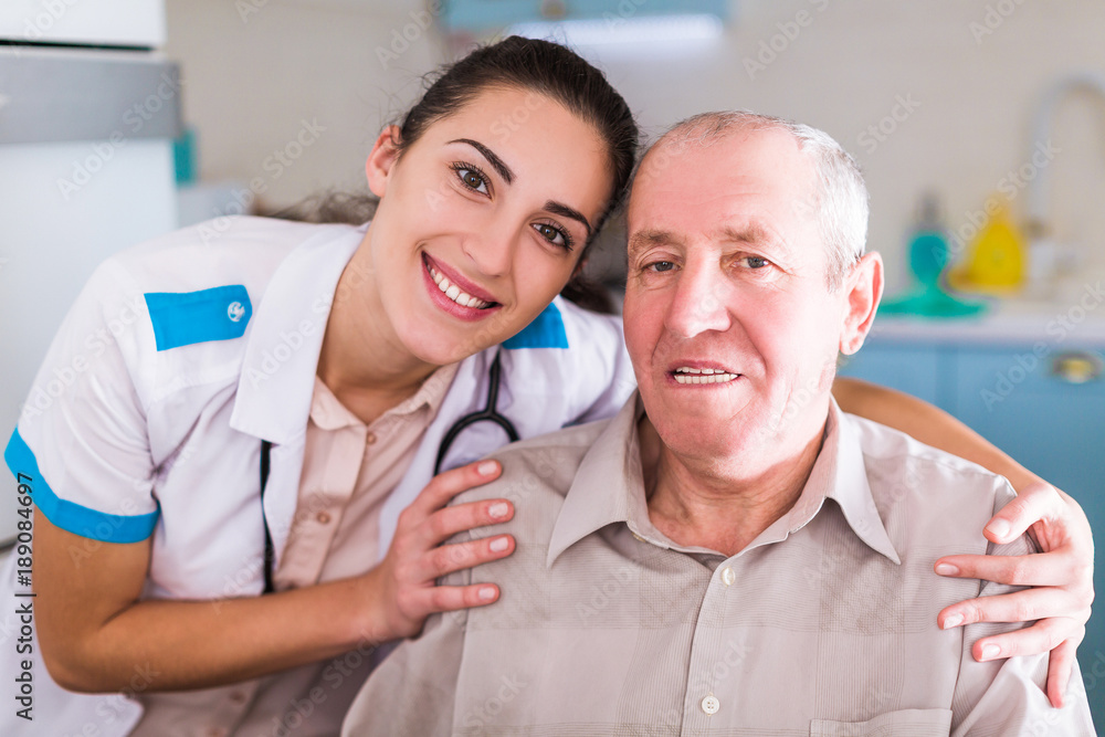 Obraz premium Portrait of the old ill man who sitting near the young smiling nurse