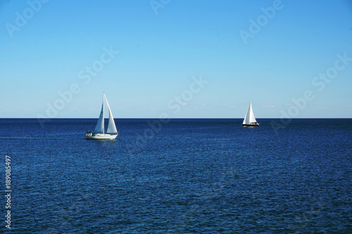 Two white sailing boats on a blue water of the Ontario lake - Toronto, Ontario, Canada