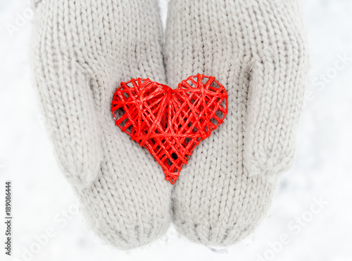 Hands in gloves holding red heart