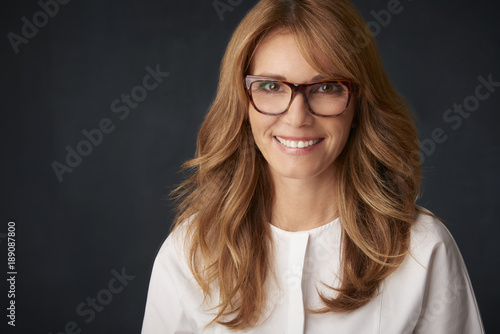 Attractive middle aged woman with toothy smile posing at studio against isolated background