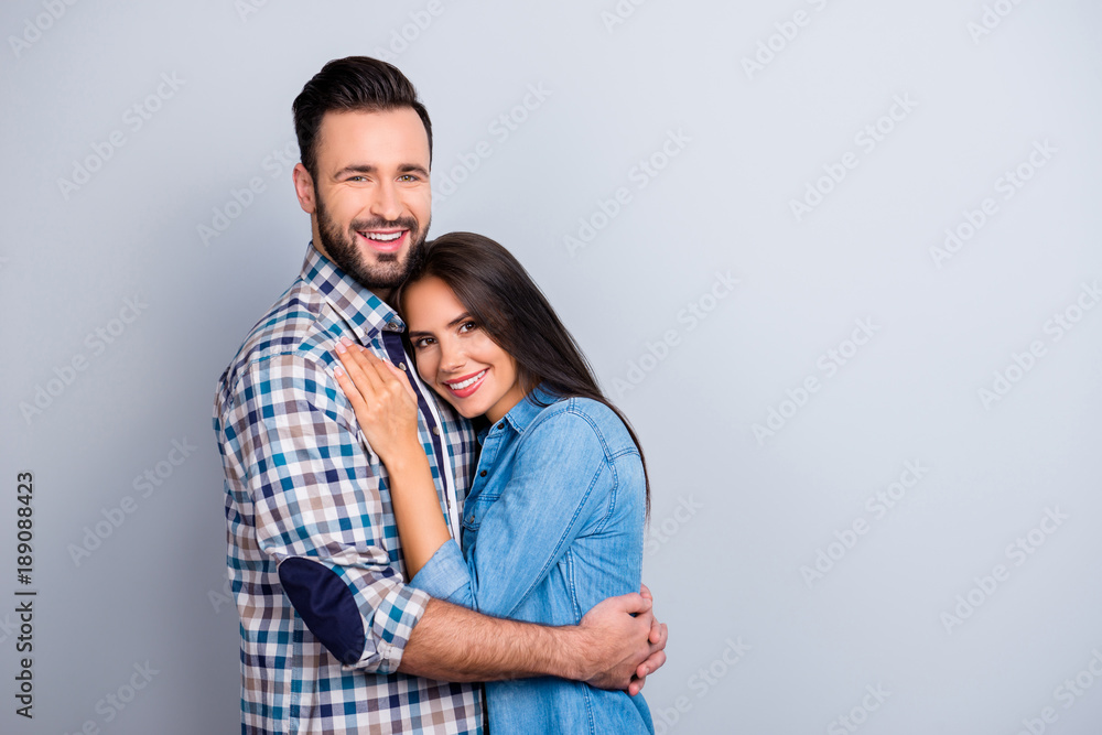 Portrait of beautiful, cheerful, positive, nice couple in shirt enjoying hug with each other, looking at camera over grey background Portrait of beautiful, cheerful, positive, nice couple in shirt enjoying hug with each other, looking at camera over grey background