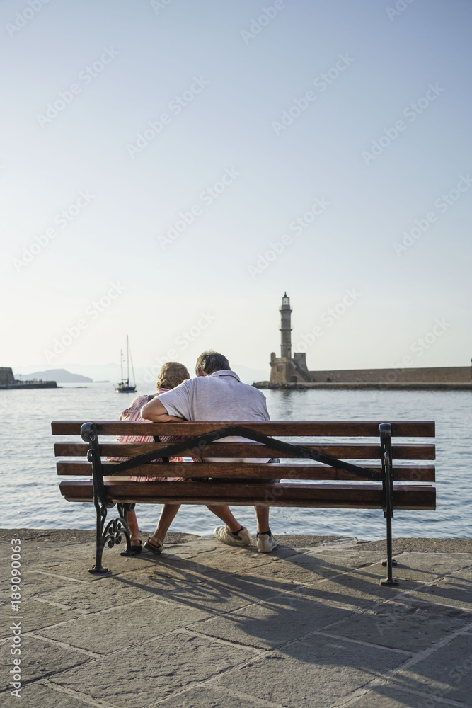 A couple sitting on bench against sea