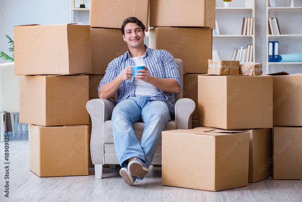 Young man moving in to new house with boxes Young man moving in to new house with boxes