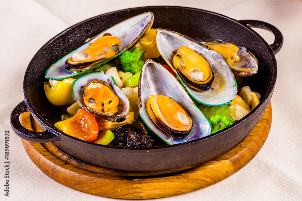Mussels with vegetables in cast-iron black pot Mussels with vegetables in cast-iron black pot