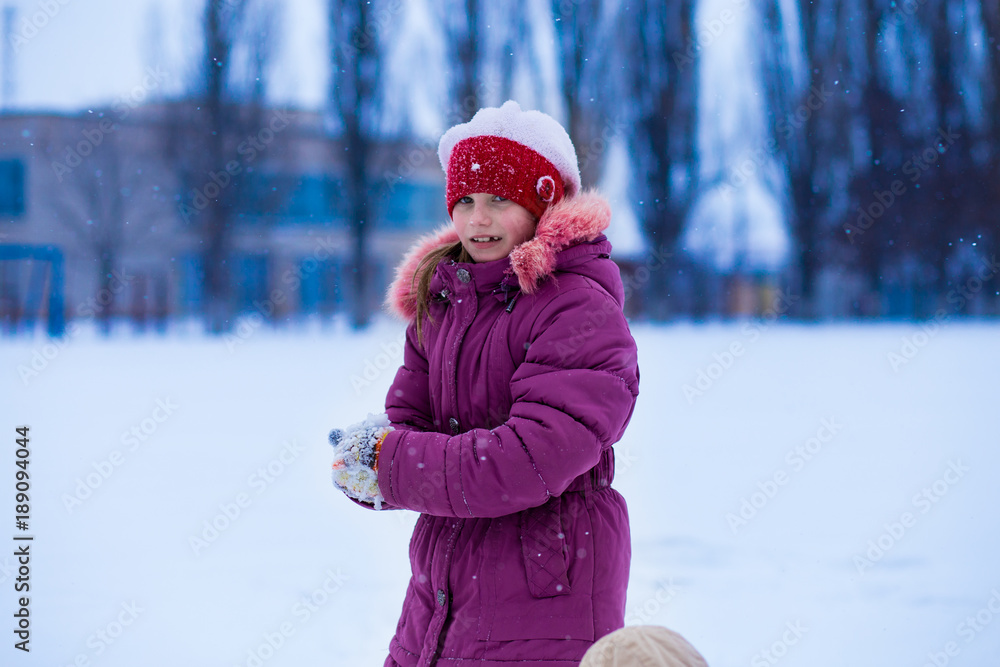 A cute little girl walking in snow park, wintertime