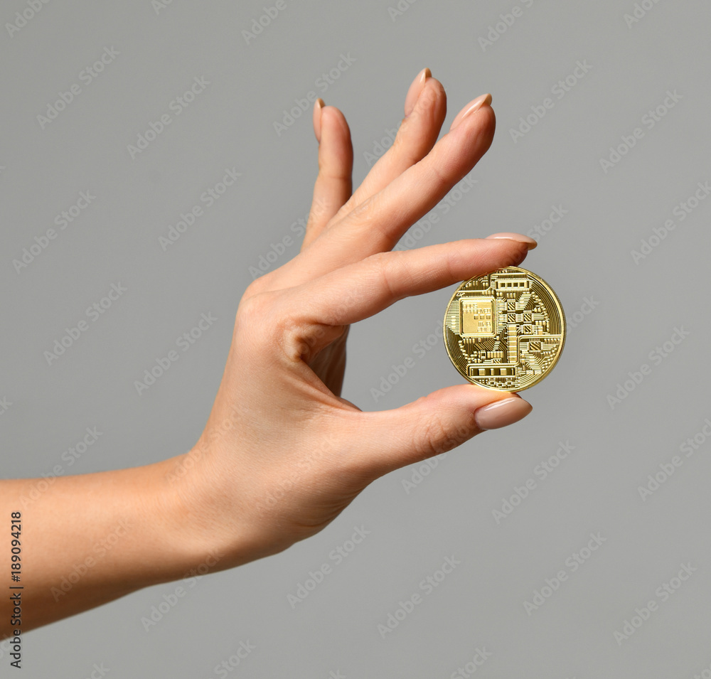 Hand hold gold bitcoin cryptocurrency on grey background. Digital currency back side