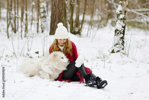 Pretty Young Woman in Snowy Winter Forest Park Walking with her Dog White Samoyed Seasonal  © milenie