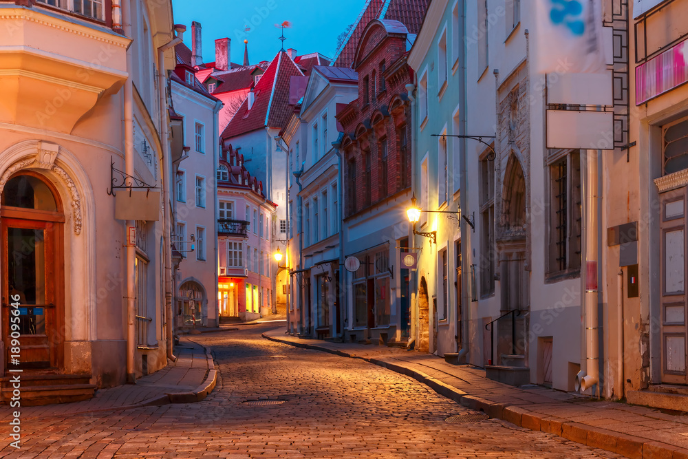 Beautiful illuminated medieval street in Old Town of Tallinn during evening blue hour, Estonia