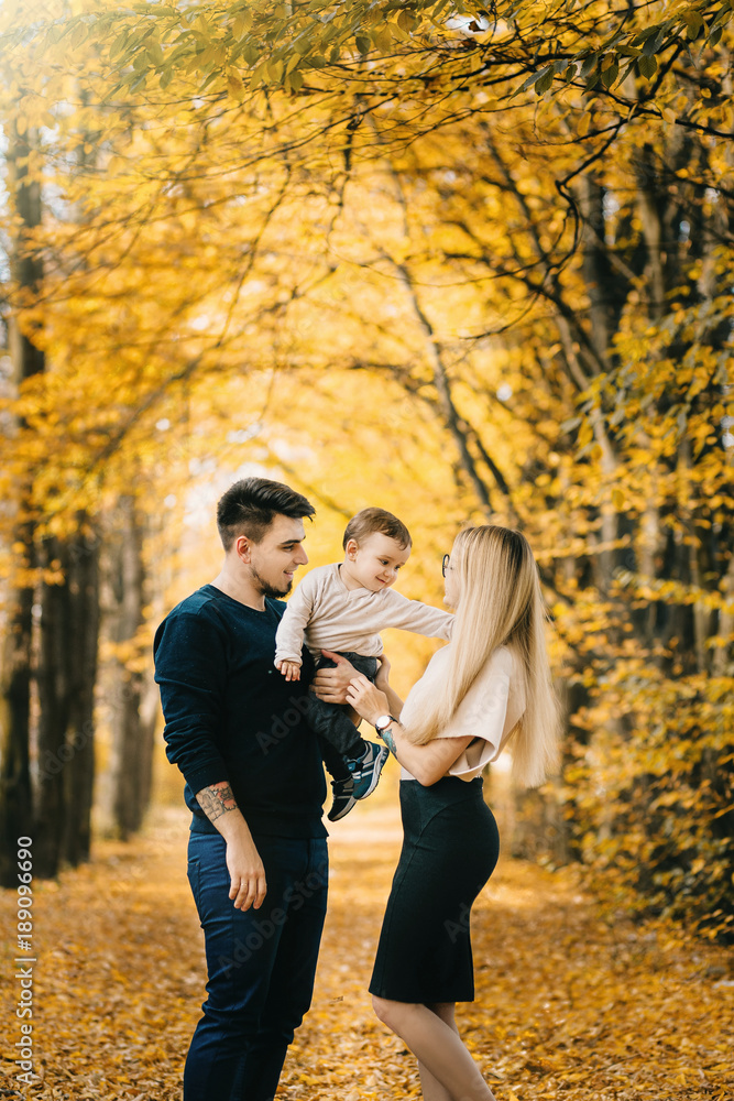 young family and newborn son posing for the camera in autumn park young family and newborn son posing for the camera in autumn park