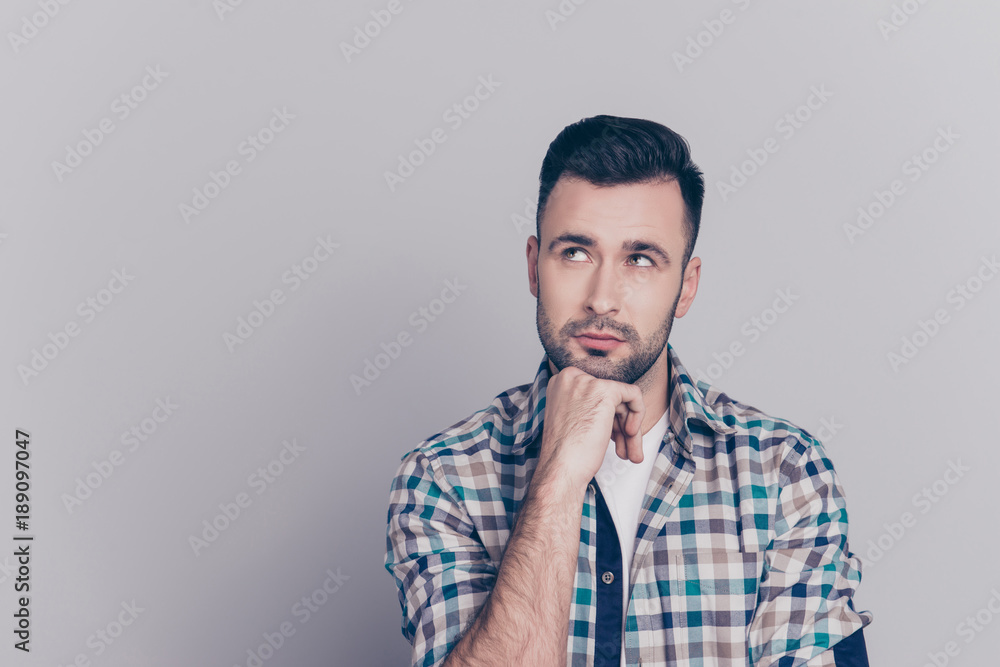 Portrait of attractive, thoughtful man holding arm on chin, having doubts, meditating, looking at copy space, standing over grey background Portrait of attractive, thoughtful man holding arm on chin, having doubts, meditating, looking at copy space, standing over grey background