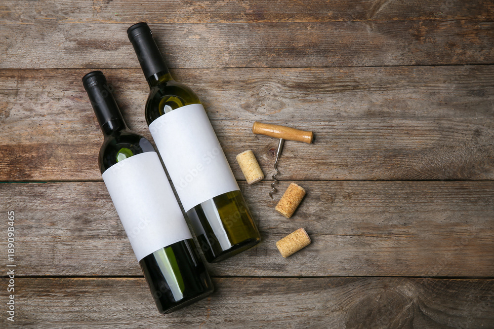 Bottles of wine with blank labels on wooden background. Mock up for design