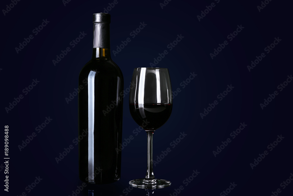 Bottle and glass with red wine on black background