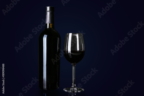 Bottle and glass with red wine on black background