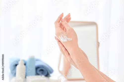 Woman applying hand cream at home