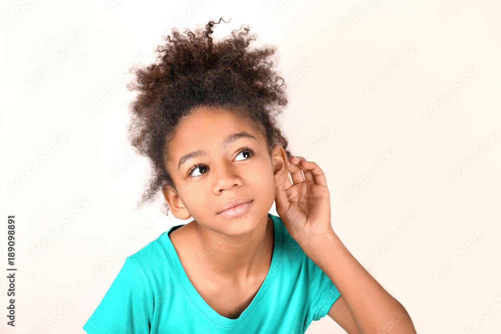 Little African-American girl with hearing problem on light background Little African-American girl with hearing problem on light background