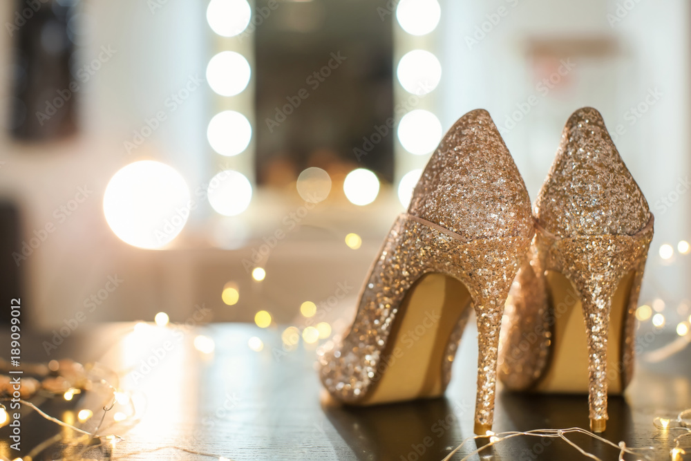 Beautiful high heeled shoes on table with fairy lights - obrazy, fototapety, plakaty 
