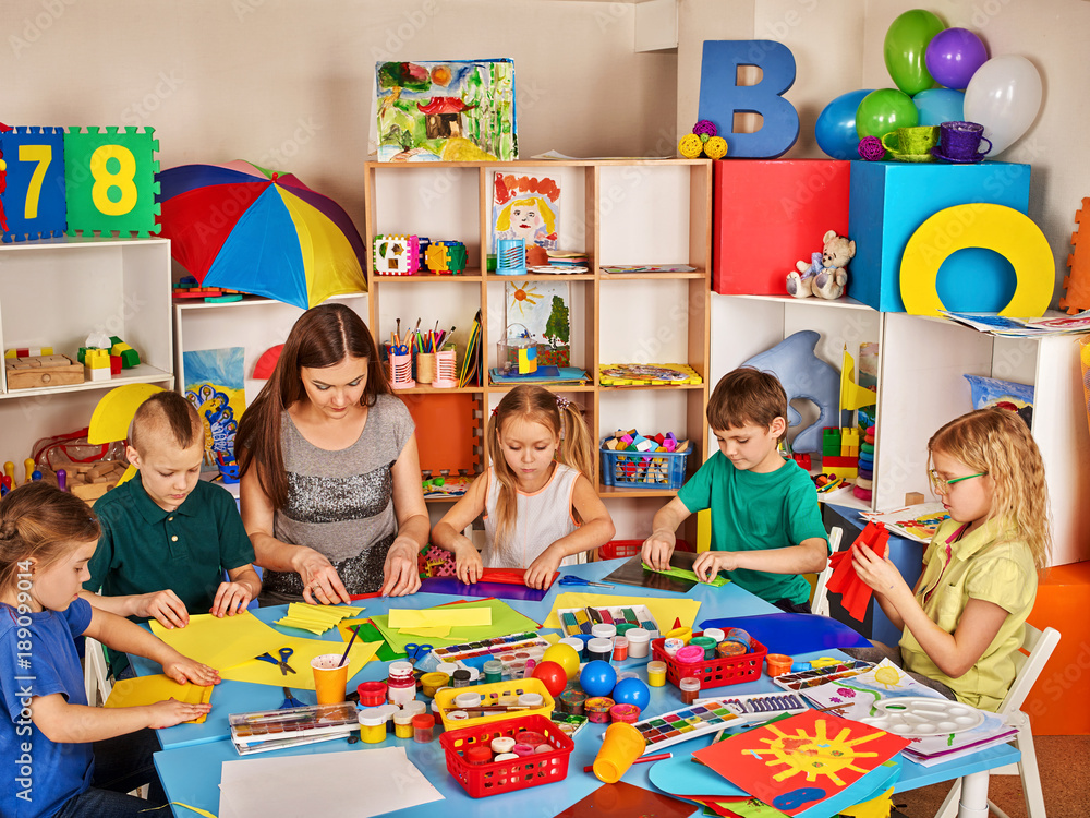 School children with scissors in kids hands cutting paper with teacher ...