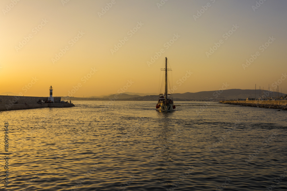 Fishermen and sailboat at sunset in Alimos marina in Athens, Greece