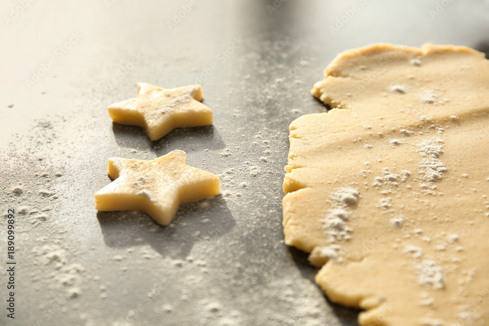 Cutting cookies from raw dough on table