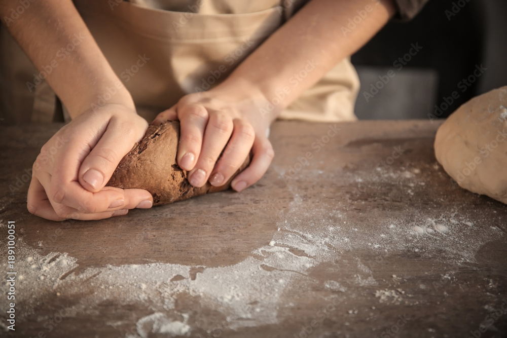 Woman kneading dough on table, closeup