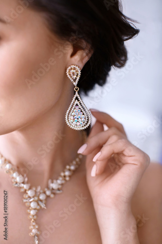 Beautiful woman with elegant jewelry on blurred background, closeup