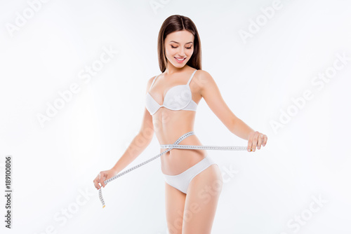 Achievement success celebrate struggling against fat concept. Beautiful slender perfect ideal excellent woman is enjoying the result of her dieting measuring waistline isolated on white background