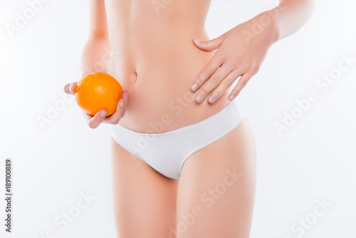 Cosmetology no fatty folds smooth flawless pure clean clear skin concept. Cropped close up photo of skinny thin beautiful sexy woman's body, palm compare skin with fruit isolated on white background