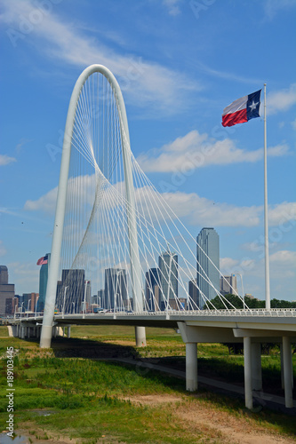 The flag of Texas flys over a highway bridge leading to downtown Dallas.