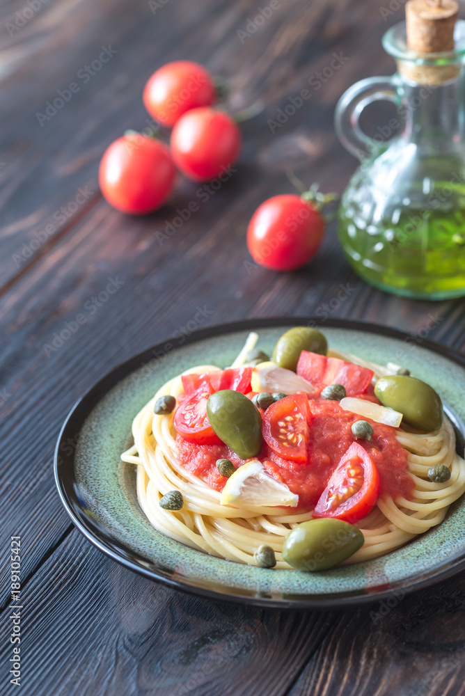 Pasta with tomato sauce, olives and capers on the plate