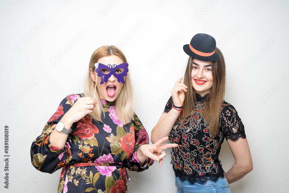 Obraz premium two girls posing party props photo booth white background studio drunk happy laugh