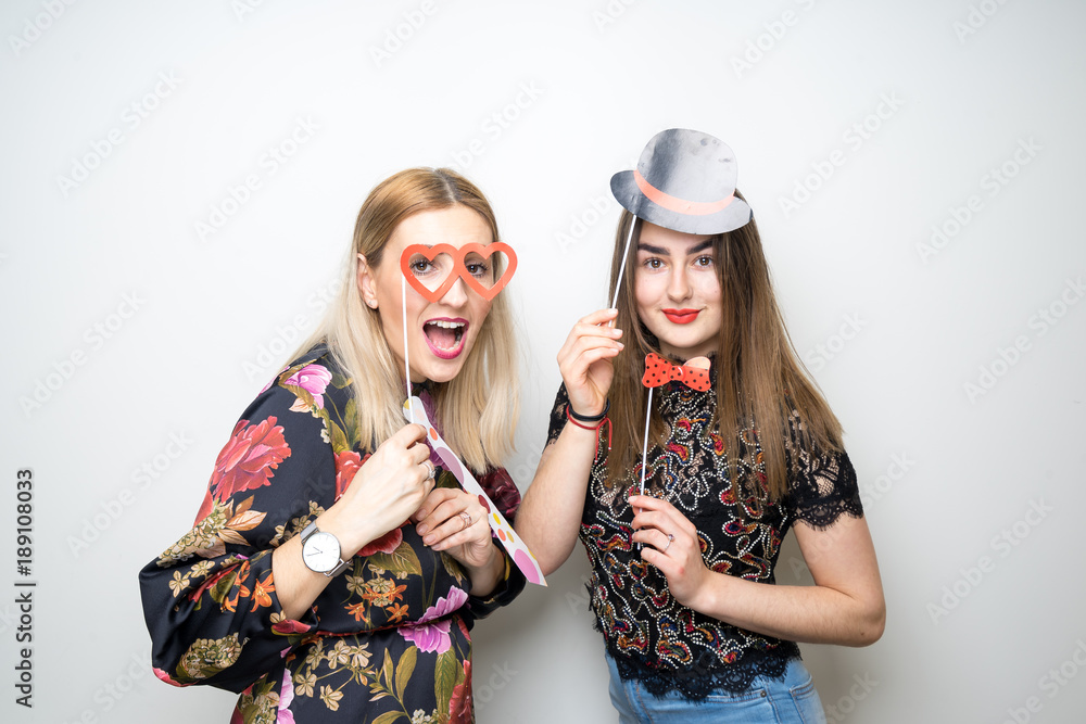 two girls posing party props photo booth white background studio drunk happy laugh