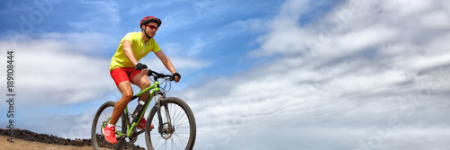 Sport athlete fitness training biking on mountain MTB bike landscape banner panorama. Copy space on blue sky background. Man cyclist riding bicycle outdoors.