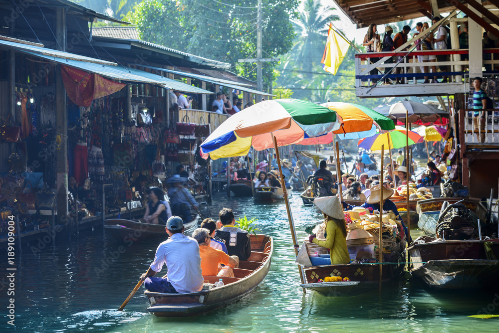 Naklejka premium Pływający targ Damnoen Saduak, turyści odwiedzający łodzie, położony w Bangkoku w Tajlandii.