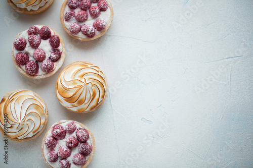 Fotografie Delicious lemon and raspberry tartlets with meringue on a white vintage plate