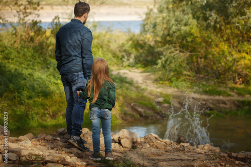 Father and daughter are standing by the river