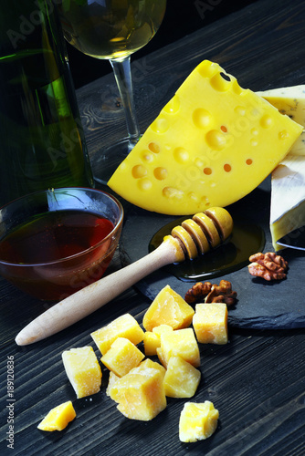 Cheese with wine and honey on a dark wooden table.