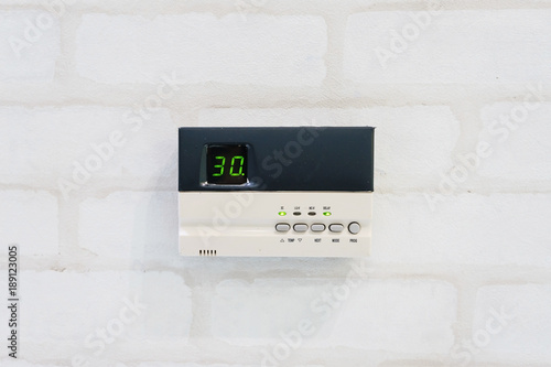 Modern programming thermostat in front of white brick wall with copyspace and text